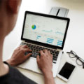 Eine Person tippt am Laptop, auf dem eine Präsentation oder ein Diagramm angezeigt wird.